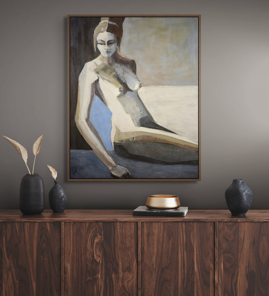 Framed painting of a nude figure on a wall above a wooden cabinet with decorative items.