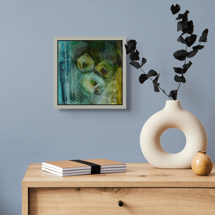 Framed abstract painting against a blue wall.